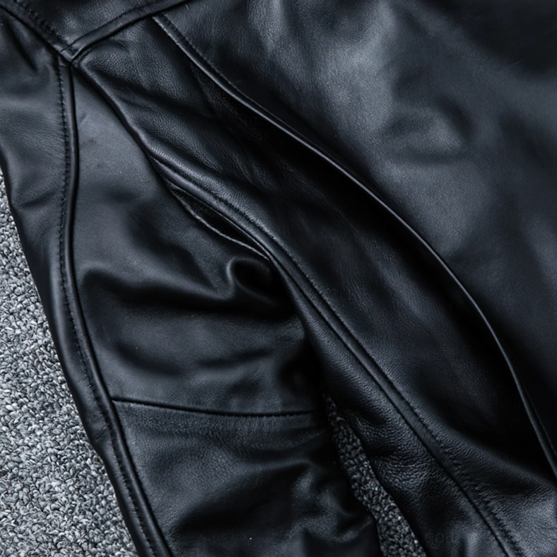 Close-up detail of smooth black sheepskin leather texture and precision stitching on jacket panel