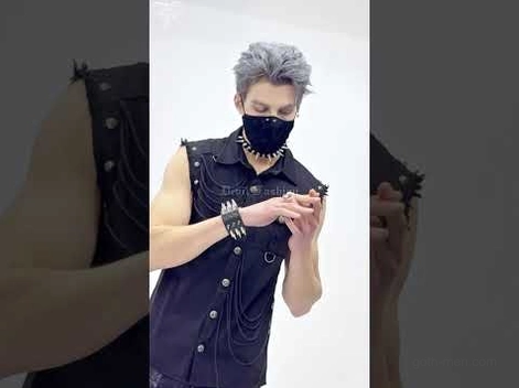 Masked male goth model wearing slim black spiked leather bracelet in side profile studio shot