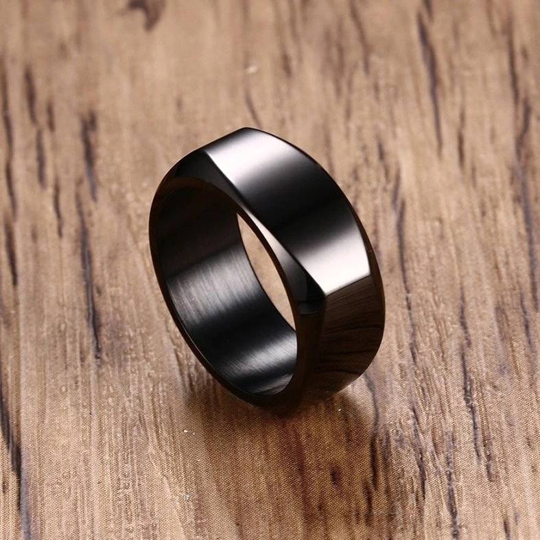 Black stainless steel geometric band ring with smooth polished surface and beveled edges, side profile on wooden surface
