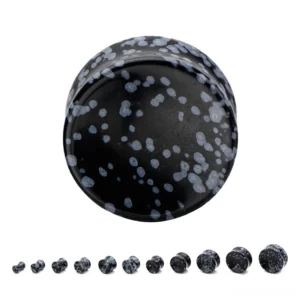 Close-up detail of natural black stone ear tunnel plugs showing speckled texture and double-flare design
