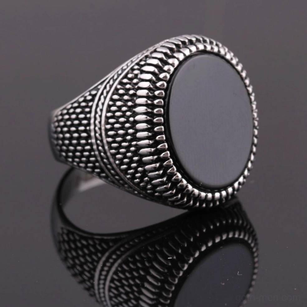 Silver and black men's signet ring dark reflective background showing contrast and finish