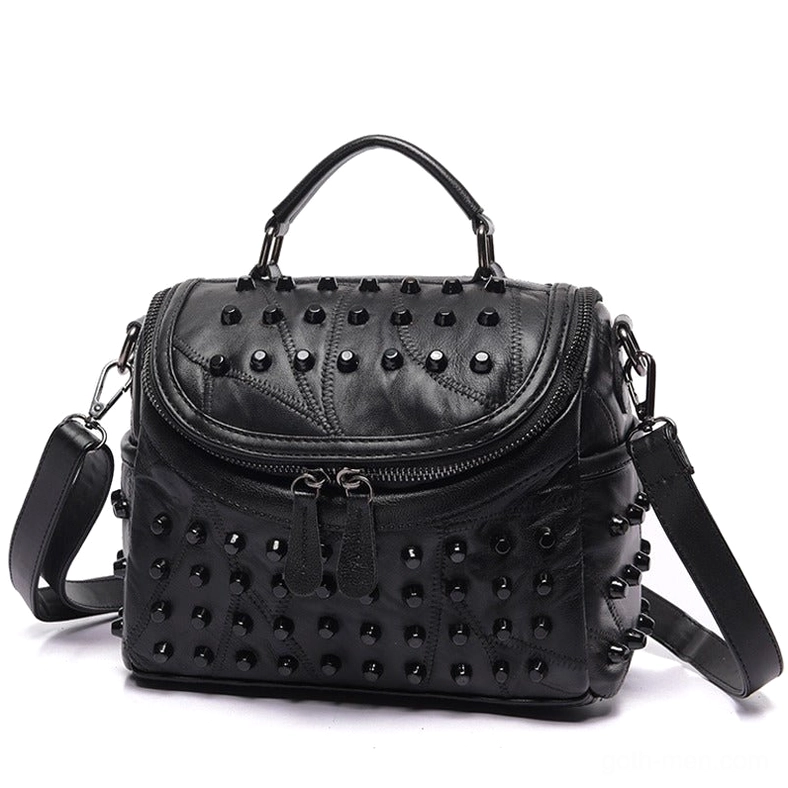 Black studded sheepskin messenger bag front three-quarter view showing dual zippers and metal rivet detailing