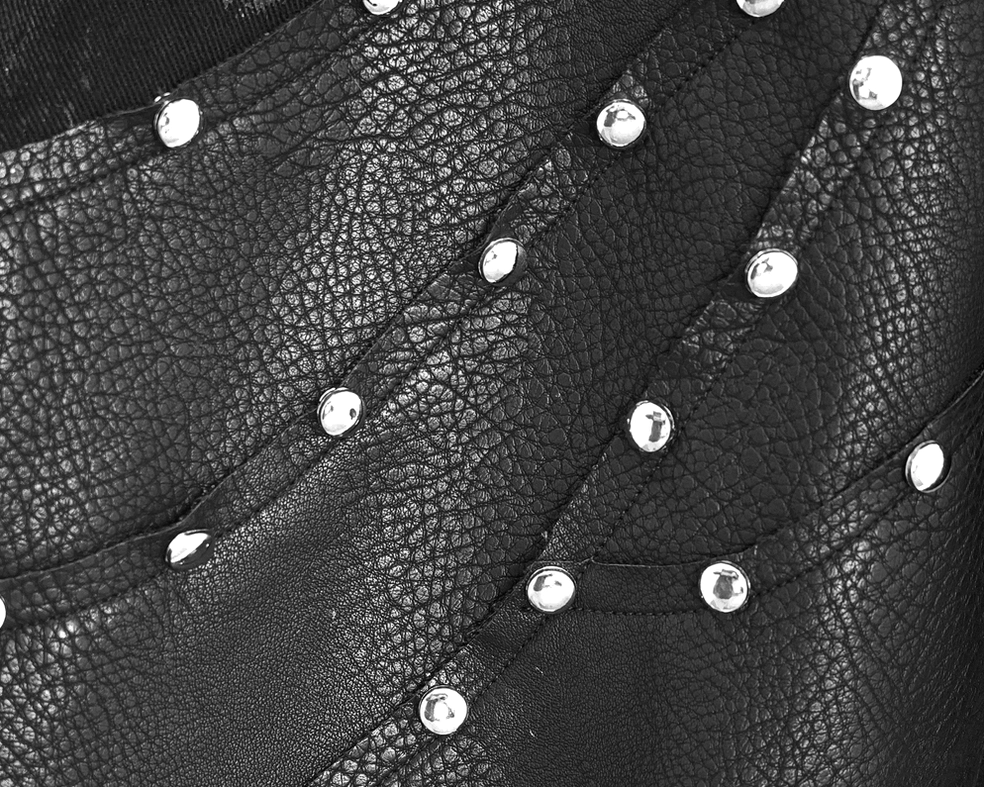 Textured fabric detail showing silver round studs and stitched seams on black gothic pants