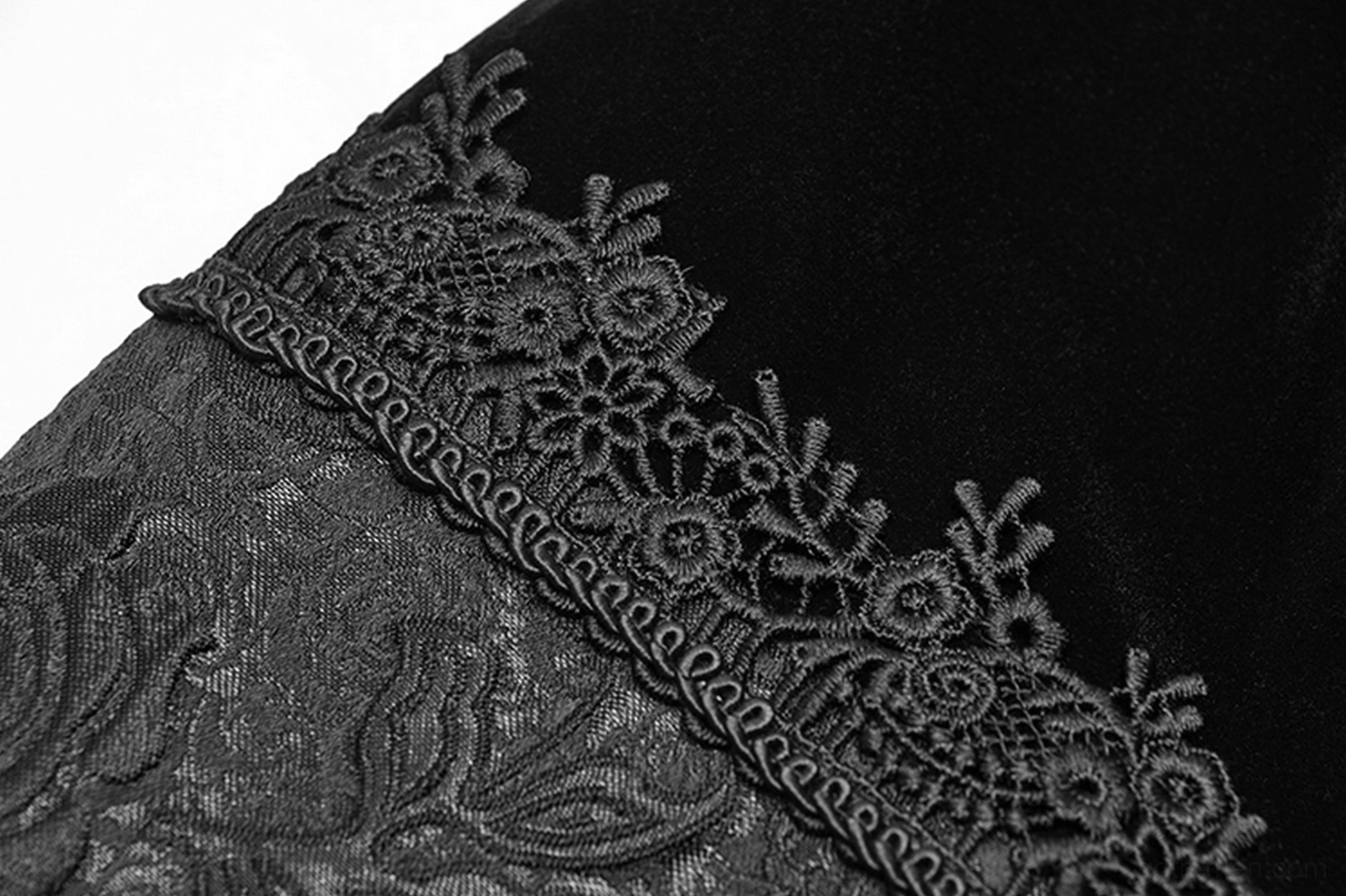 Close-up detail of delicate floral embroidered lace trim accent against black velvet base material