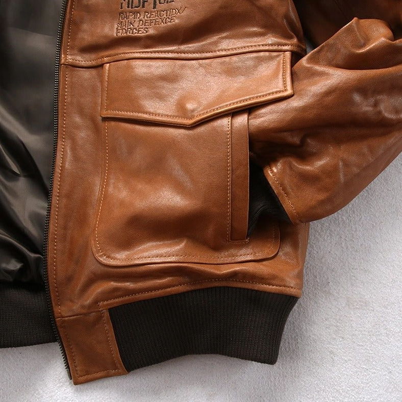 Leather bomber jacket chest pocket close-up showing flap design and ribbed hem construction detail