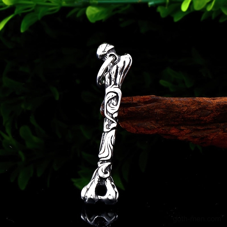 Carved bone pendant with antique silver finish and intricate vine pattern carvings displayed with vintage props