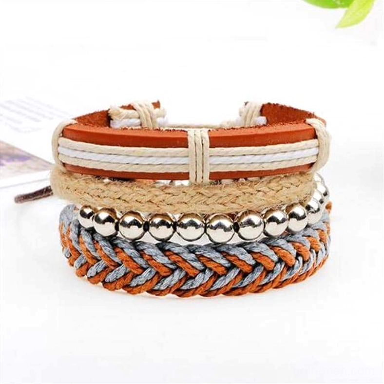 Three-quarter front view of 4-piece brown gothic leather bracelet collection displayed on tabletop with natural styling elements and green leaf decoration