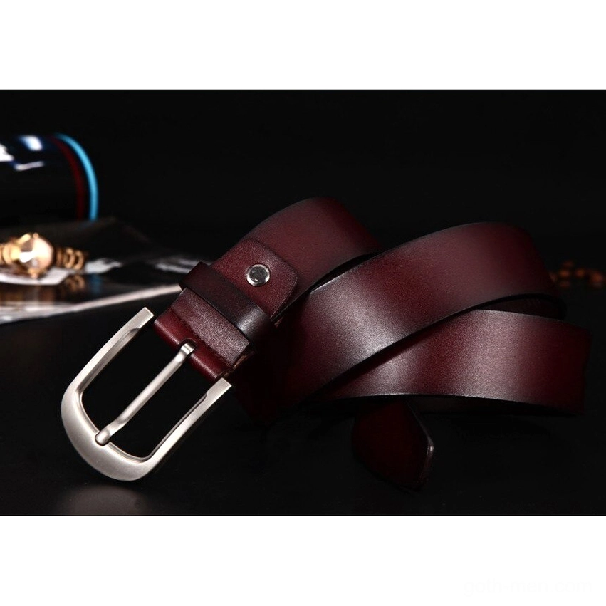 Deep brown genuine cowhide belt with silver metal buckle, flat lay on dark background with accessories