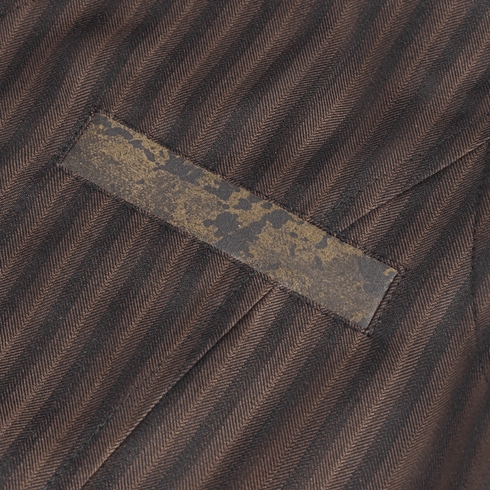 Close-up detail of brown pinstriped gothic waistcoat distressed leather trim accent strip on pinstripe base