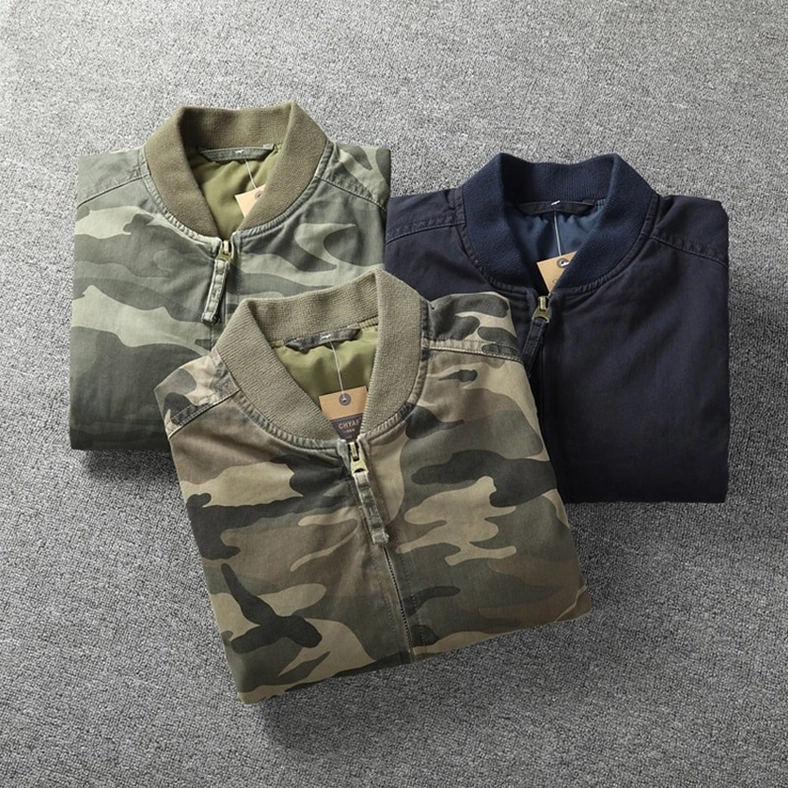 Three color variants of military camo denim zip jackets folded display, overhead view showing jungle green light tone and navy options