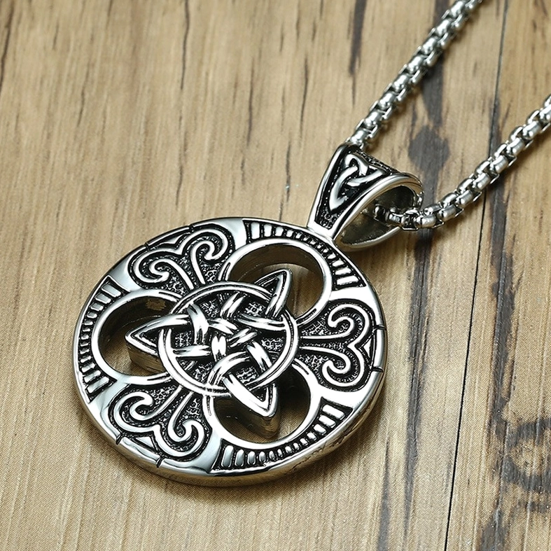 Celtic knot pendant top oblique view intricate scrollwork carved details wooden background