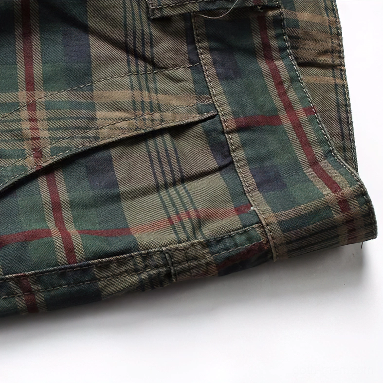 Macro close-up of cross-stitched seam on tartan plaid shorts with green, red and navy threads