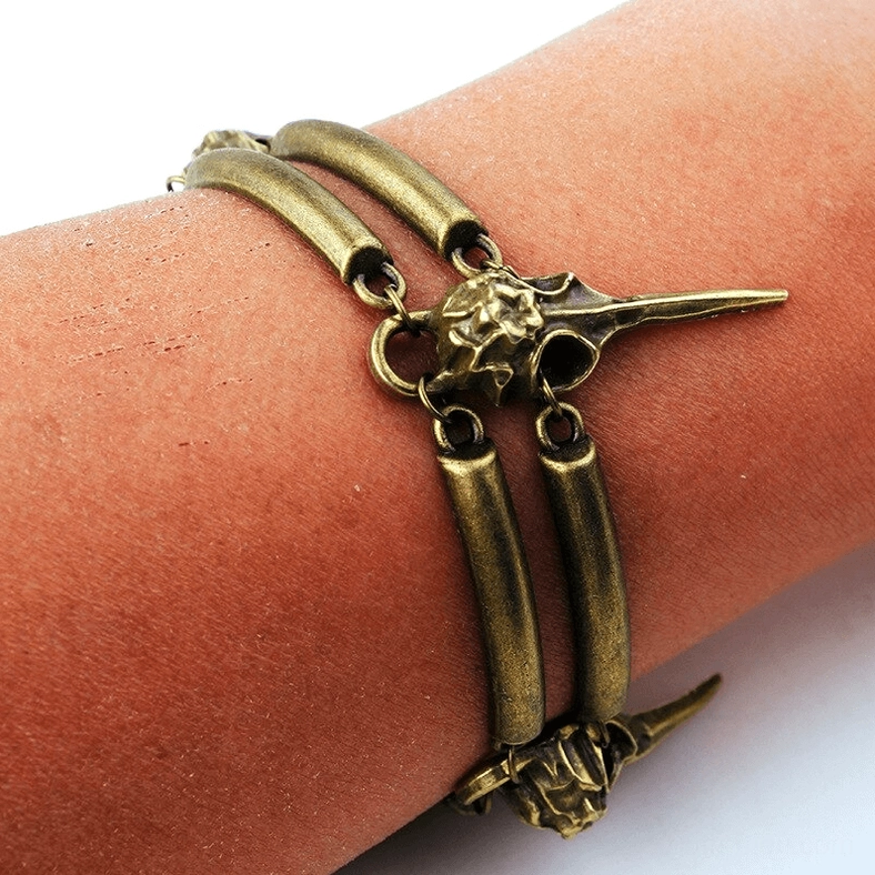 Close-up of worn gothic crow skull bracelet on wrist front view highlighting antique bronze finish and decorative details