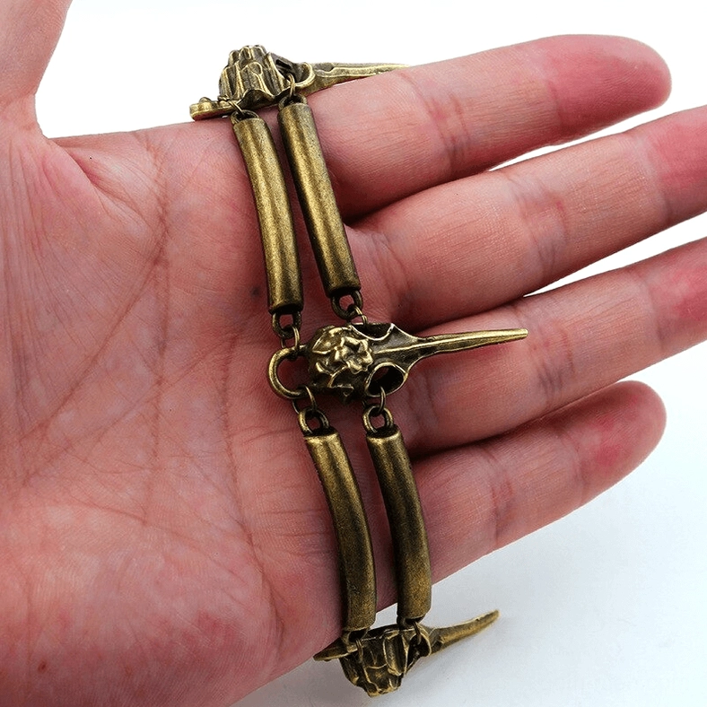 Double layer gothic crow skull bracelet held in palm showing intricate bone-shaped links and detailed bird skull pendants
