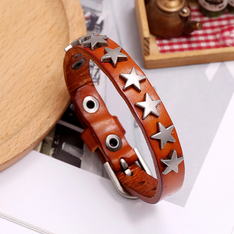 Dark brown distressed star leather gothic bracelet with antique silver rivets on vintage tabletop with period decor and teacup
