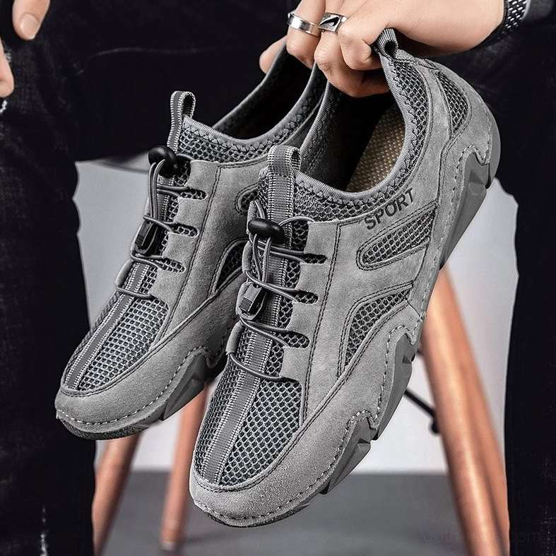 Charcoal grey dark gothic casual sneaker pair - hands holding shoes with studio stool setting