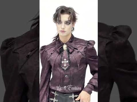 Gothic male model wearing burgundy cravat with cross belt detail on dark backdrop