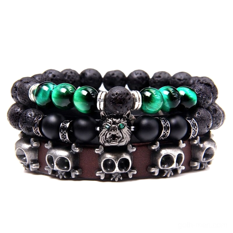 Dark trinity layered gothic bracelet stack with natural stone beads, skull charms, wolf pendant, and vintage braided leather straps on white background