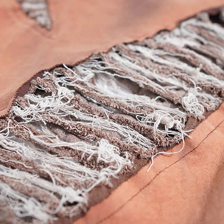 Extreme close-up of intentional ripped frayed patch on distressed gothic T-shirt showing vintage worn texture