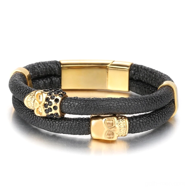 Double-layer black leather bracelet with gold-tone metal skull decorations and magnetic closure, front-facing view
