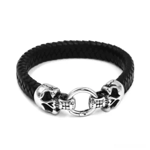 Gothic double skull leather bracelet with braided black leather and silver stainless steel skull clasps, front flat lay view