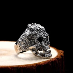 Dragon skull biker ring side profile showing detailed relief carvings on vintage wooden display stand