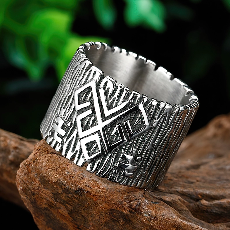 Large embossed rune motifs on gothic ring displayed three-quarter angle on wooden surface with natural foliage background