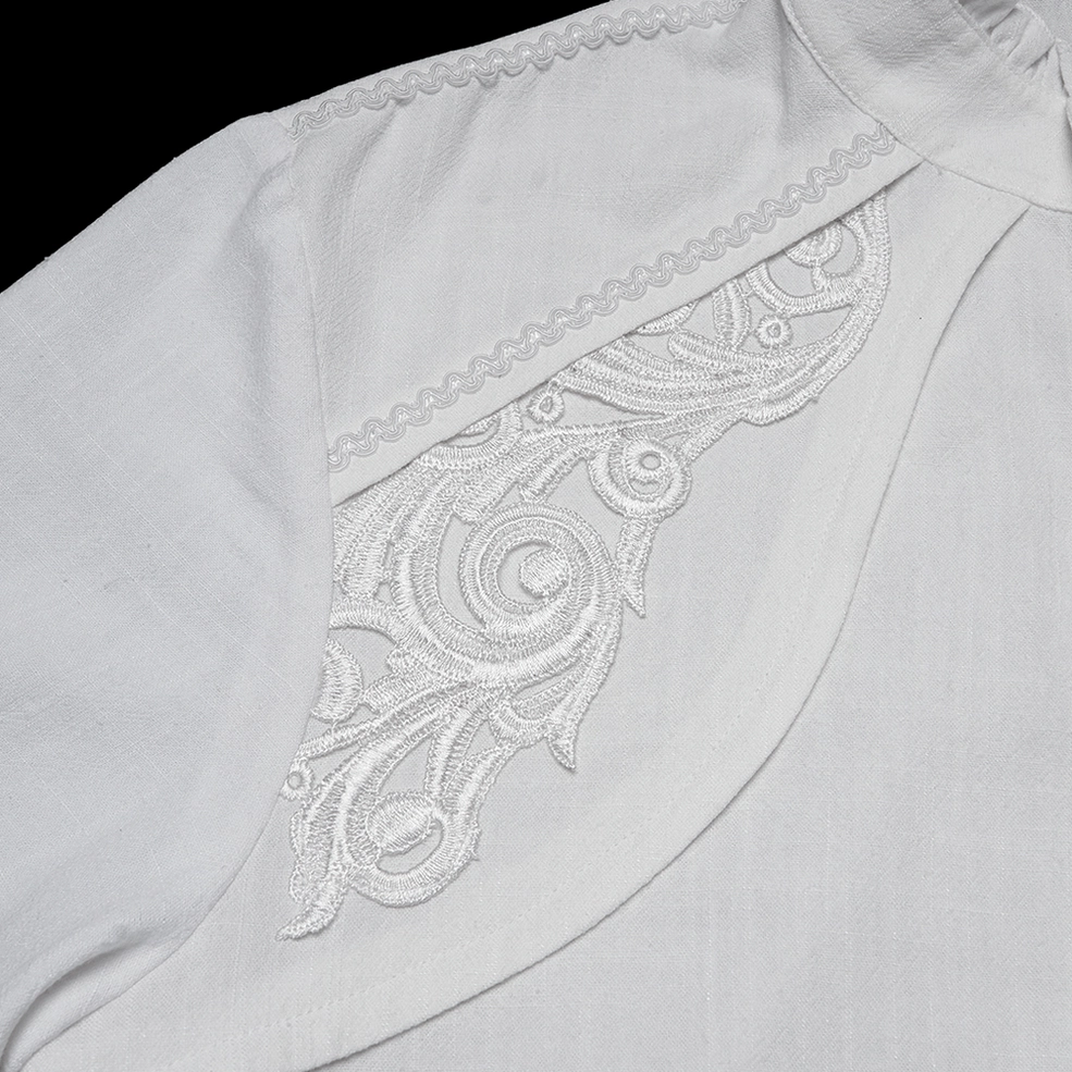 Macro photography of intricate shoulder scroll embroidery and decorative stitching trim on white gothic shirt