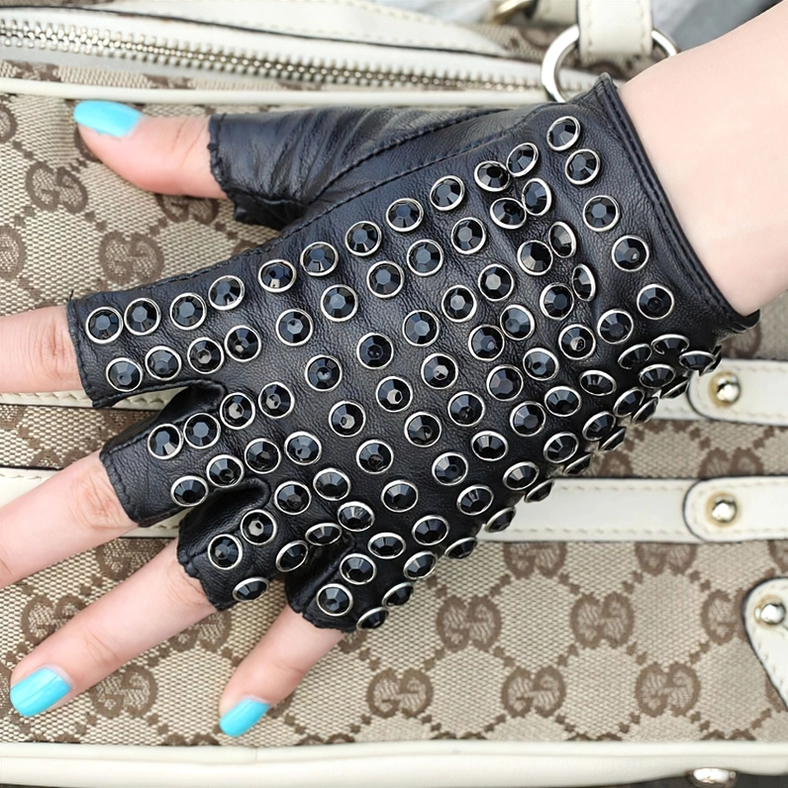 Black fingerless leather gloves styled with designer purse and blue nail polish, half-finger rivet design close-up