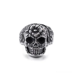 Ornate floral skull ring silver stainless steel front view, embossed flower patterns around skeletal face, gothic memento mori jewelry