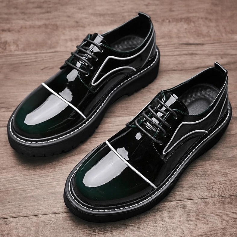 Pair of dark green patent leather lace-up platform shoes overhead flat lay on wooden surface