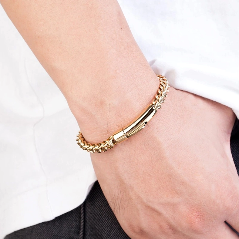 Gold stainless steel gothic bracelet worn on male model wrist - close-up side view daily wear