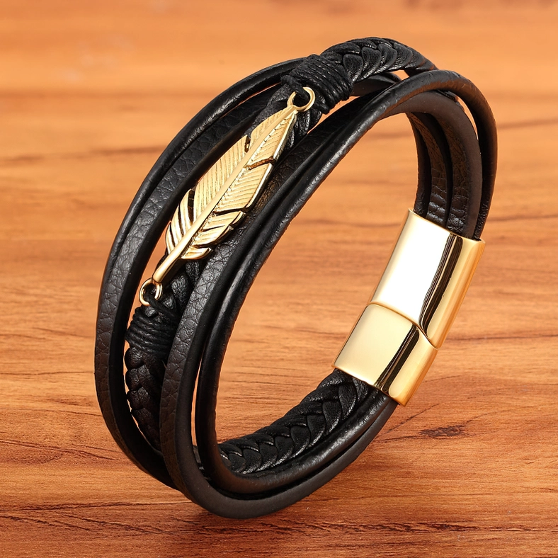 Gold hardware gothic leather bracelet with braided leather and gold feather charm, side profile on wood surface