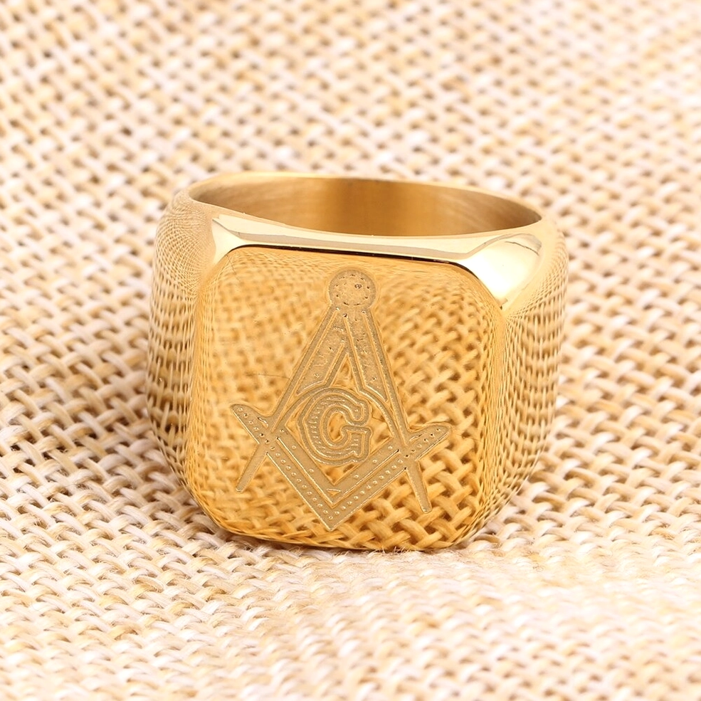 Gold Masonic signet ring polished stainless steel finish against burlap fabric, gothic luxury aesthetic