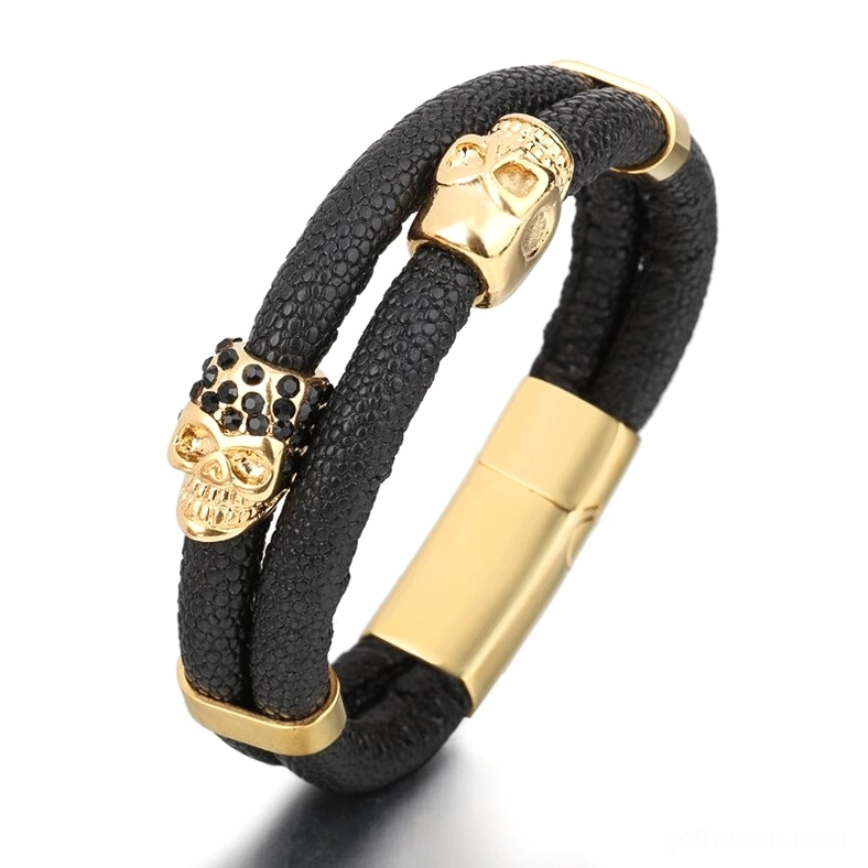 Gold-tone stainless steel magnetic skull bracelet with black genuine leather and dual skull embellishments, front angle