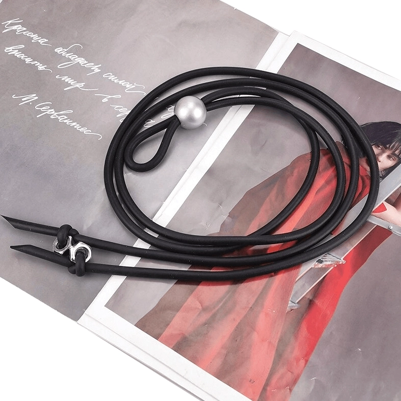 Angled flat lay of black rubber gothic necklace with pearl bead and metal screw accents, product photography detail