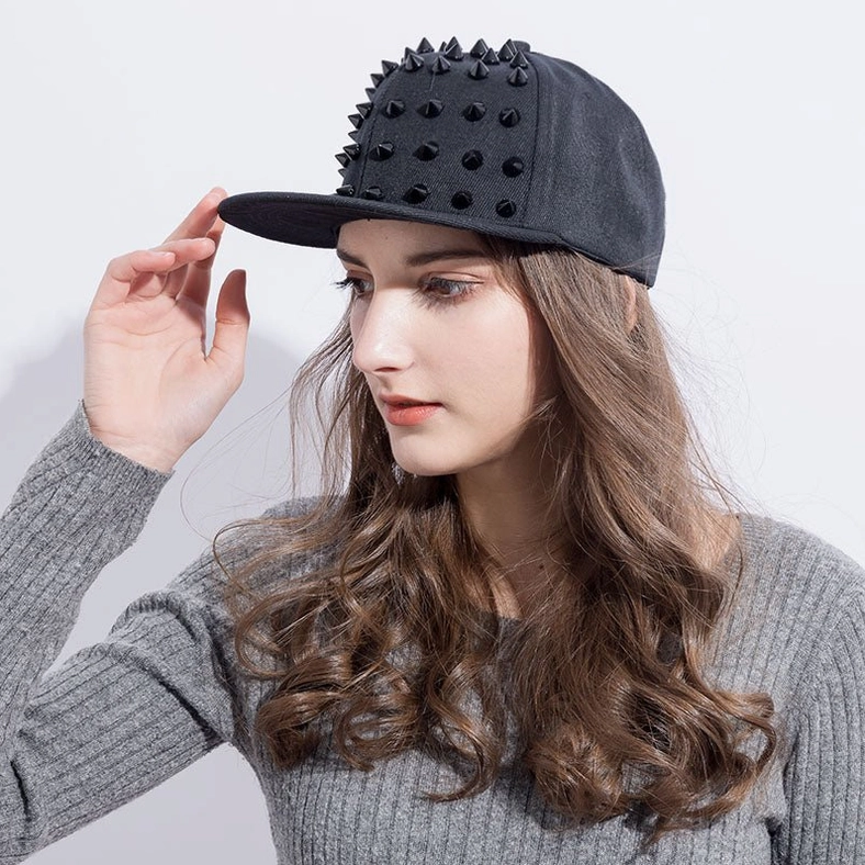 Female model wearing gothic spike snapback cap from left angle, alternative fashion styling with grey ribbed top