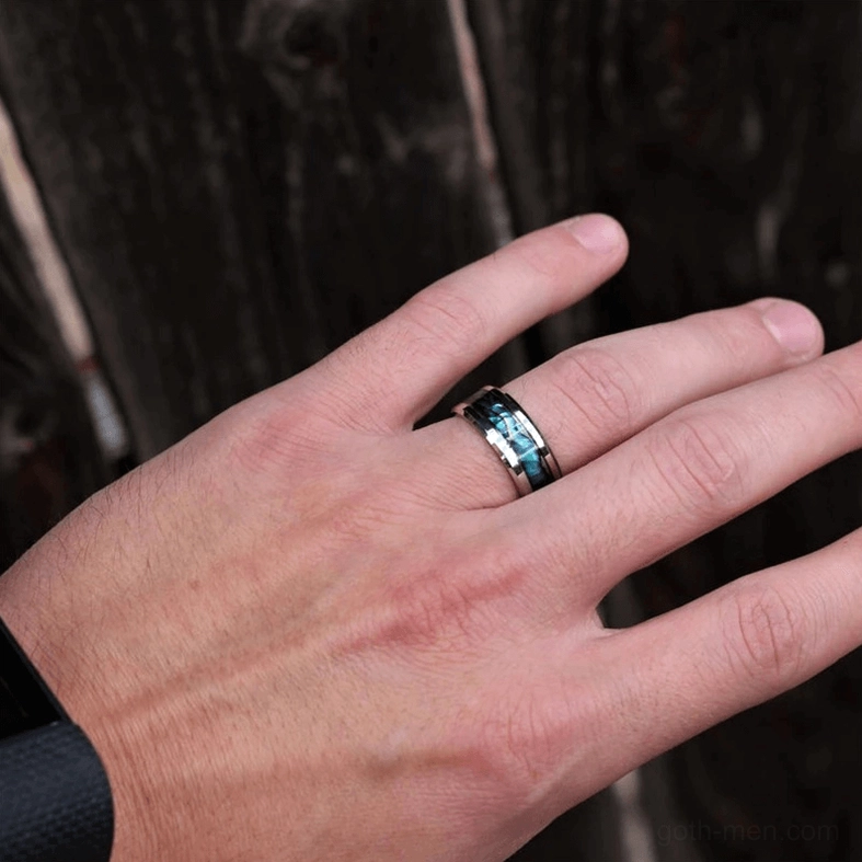 Unisex abalone inlay stainless steel ring on male hand with iridescent shell against dark wood
