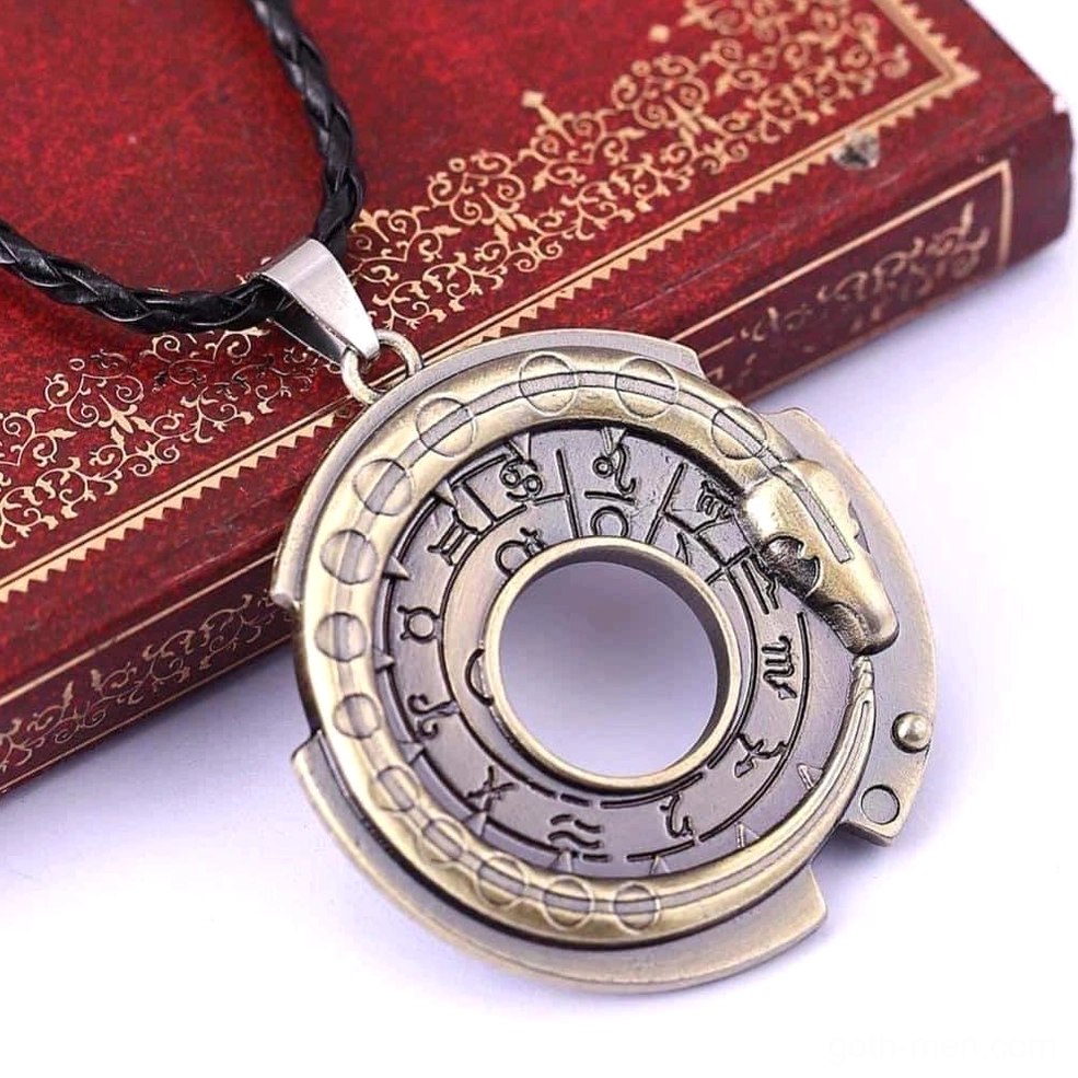 Gothic serpent pendant with hollow ring design and snake detail displayed on red gilded vintage book, bronze metal with leather rope chain