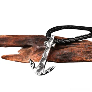 Polished silver anchor pendant with geometric faceted texture and black woven rope chain, angled side view with driftwood styling