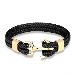 Gold polished stainless steel anchor charm on black leather rope braided bracelet, flat lay photography