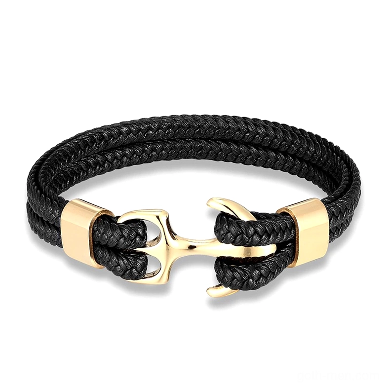 Gold polished stainless steel anchor charm on black leather rope braided bracelet, flat lay photography