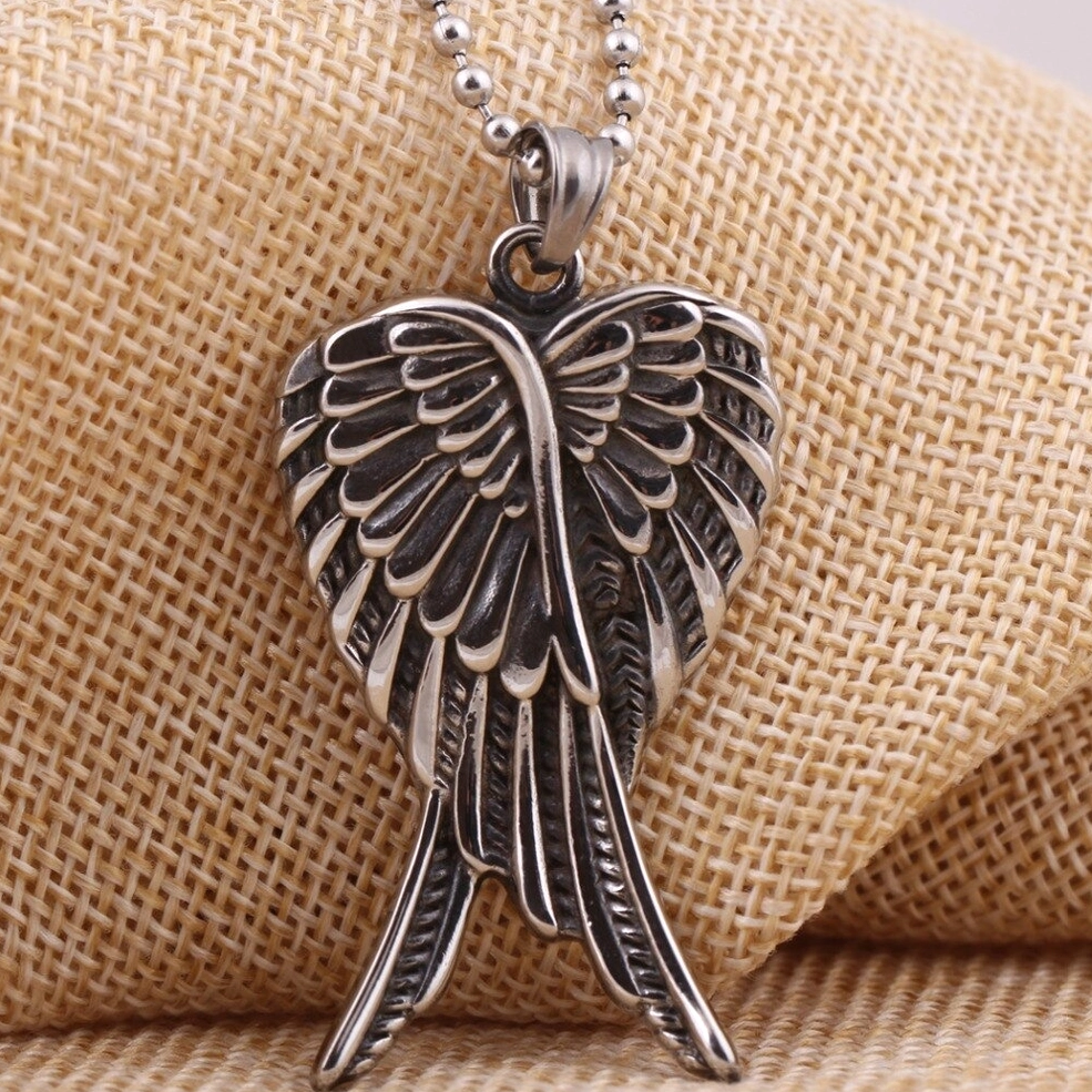 Antique overlapped angel wings pendant oblique angle showing intricate feather carving detail