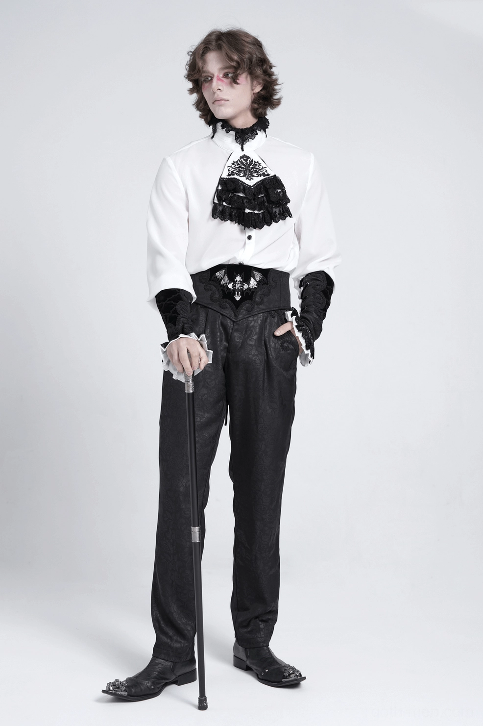 Gothic arm gauntlets worn by male model in formal goth ensemble with high-waisted trousers and matching jabot collar, front studio shot with white background