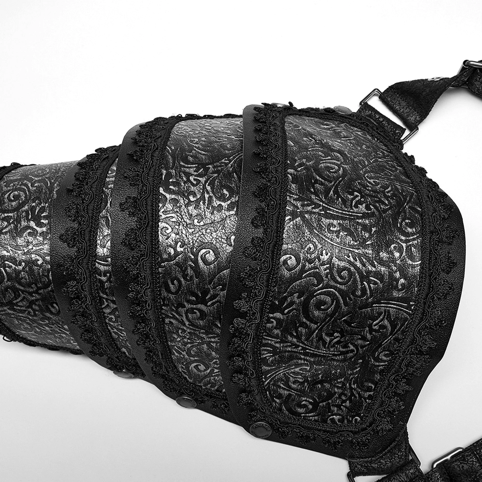 Close-up flat lay of cracked embossed faux leather armor pad with vintage scroll engraving and metal rivet fasteners