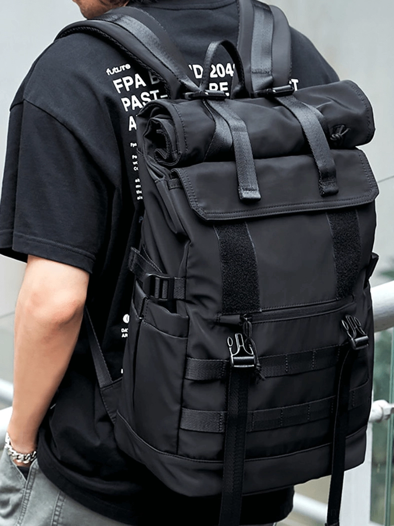 Male model wearing black gothic tactical backpack outdoor balcony setting styled with casual black t-shirt and jeans