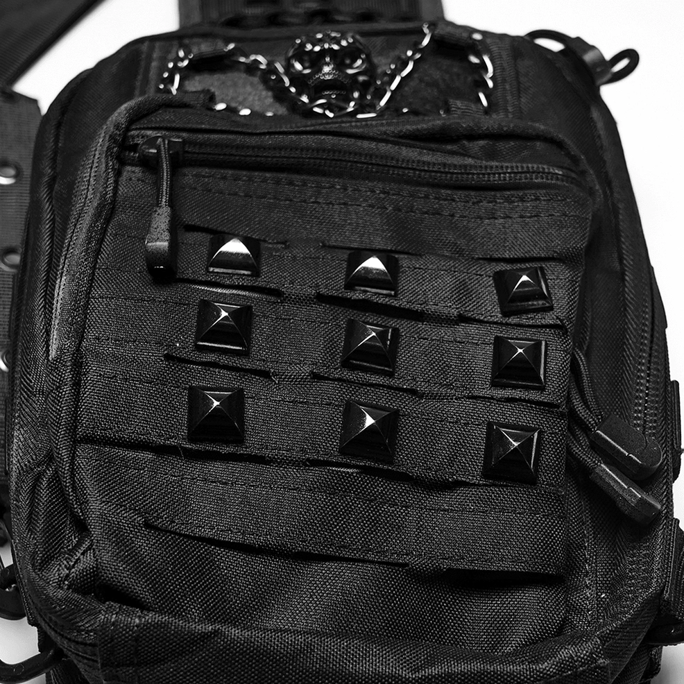 Close-up detail of pyramid studs and metal skull ornament on gothic crossbody bag front