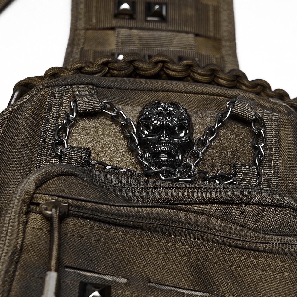 Close-up detail of gothic backpack front decoration featuring metal skull ornament, linked chain, and pyramid studs