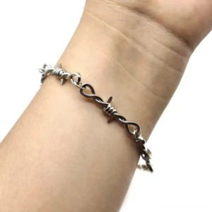 Gothic barbed wire bracelet worn on wrist, silver twisted metal chain design with industrial edge
