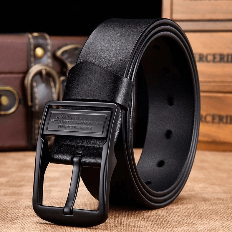 Black gothic leather belt showing punched adjustment holes and engraved matte buckle on vintage background